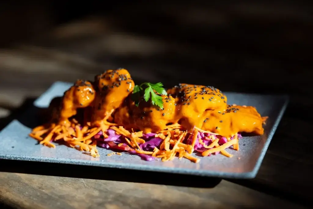 Gochujang chicken with black sesame seeds on a bed of slaw