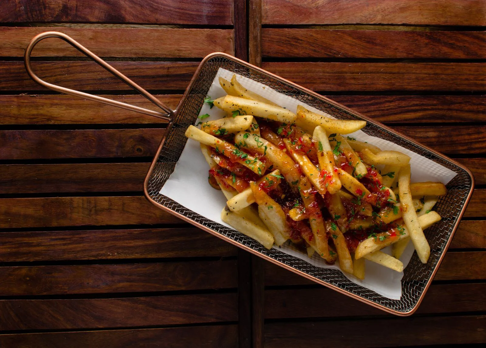Seasoned chips with chilli and spring onion in a metal basket