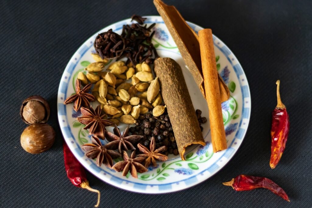 Whole spices for a masala dabba bowl: green cardamom, cloves, star anise, cassia bark, black pepper and dried red chillies